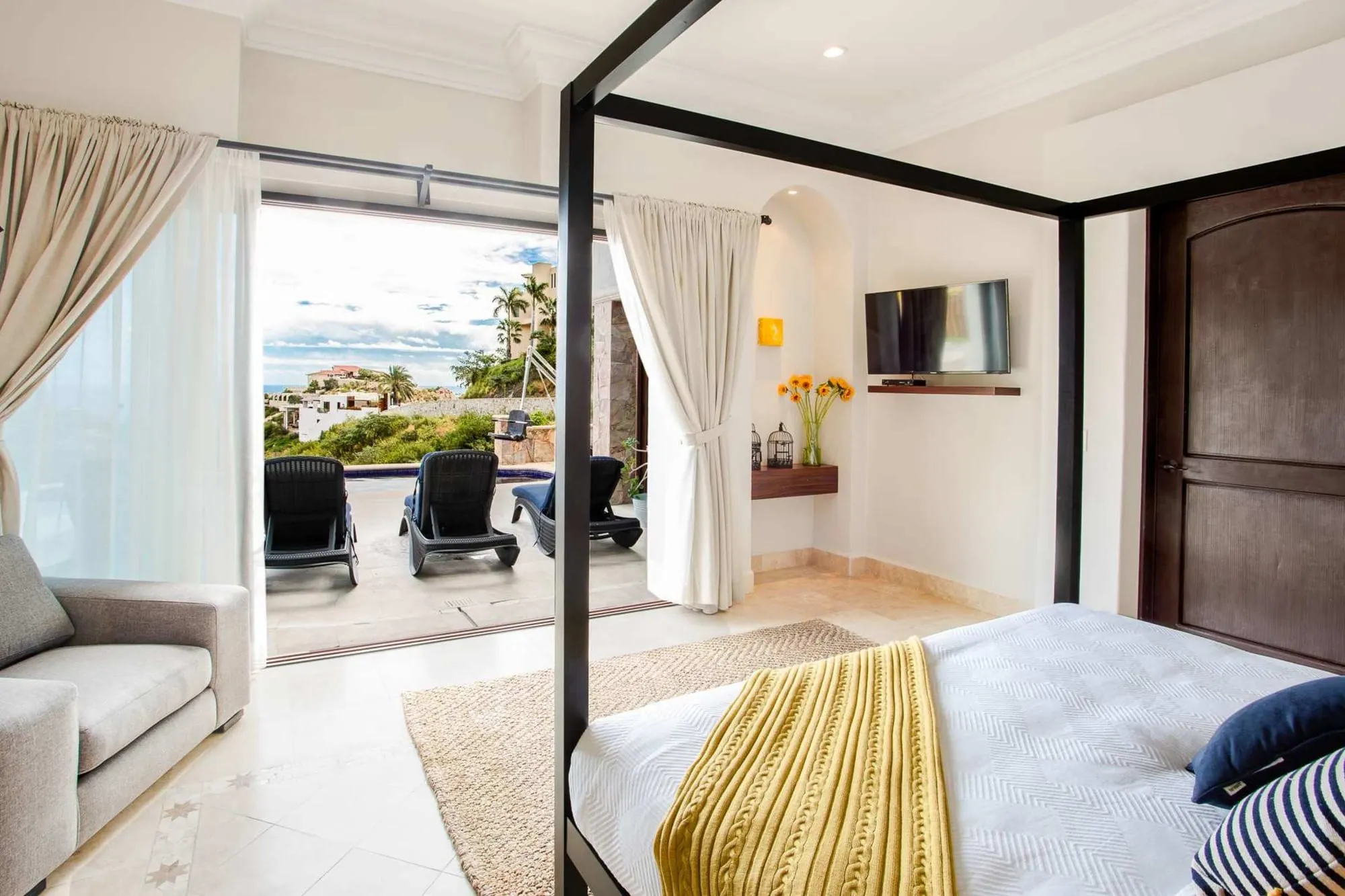 A bedroom at the Pedregal villa, its doors open to the terrace and the sea