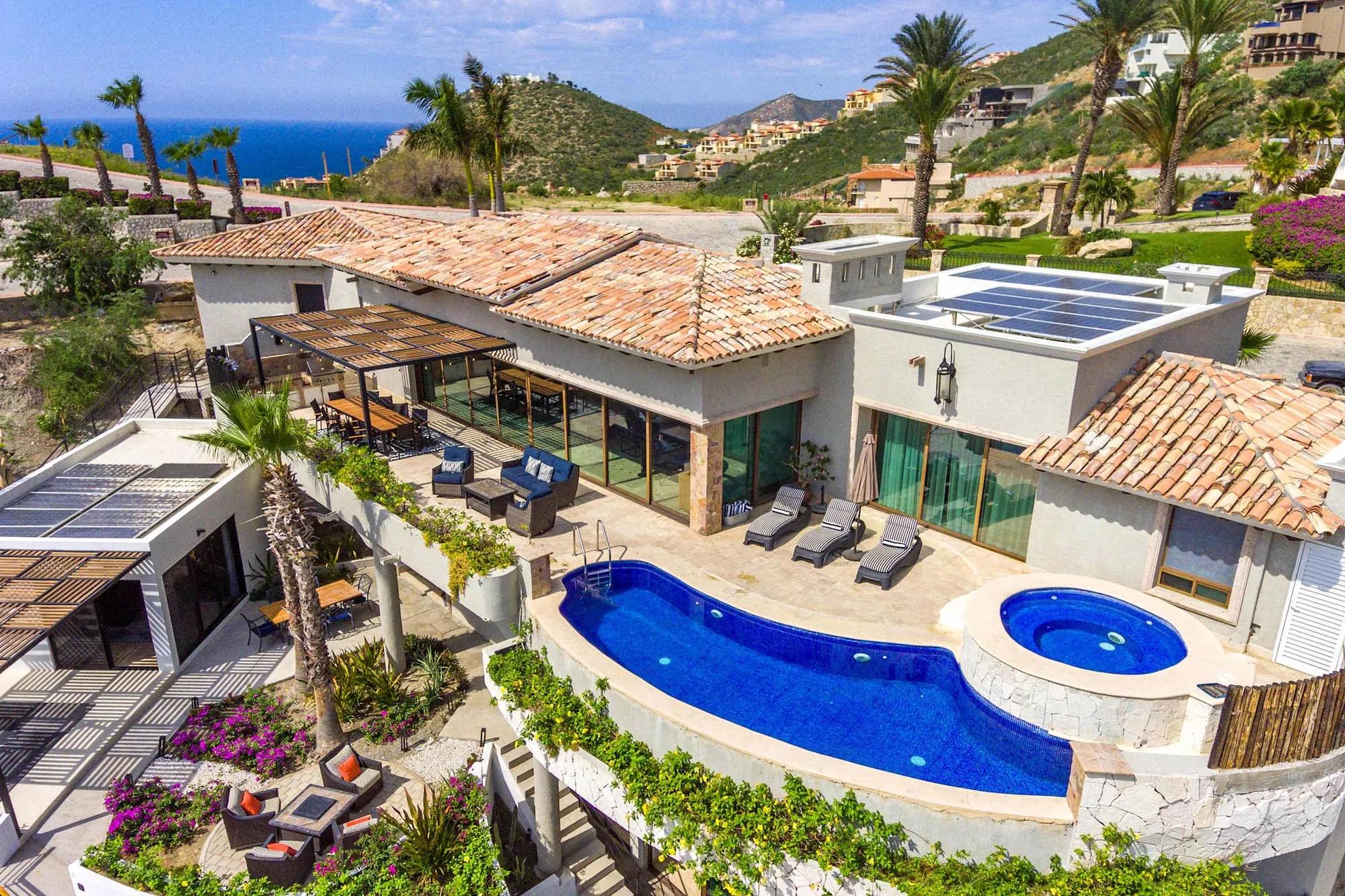 The pool and hot tub at the Pedregal villa, the ocean and the hillside beyond