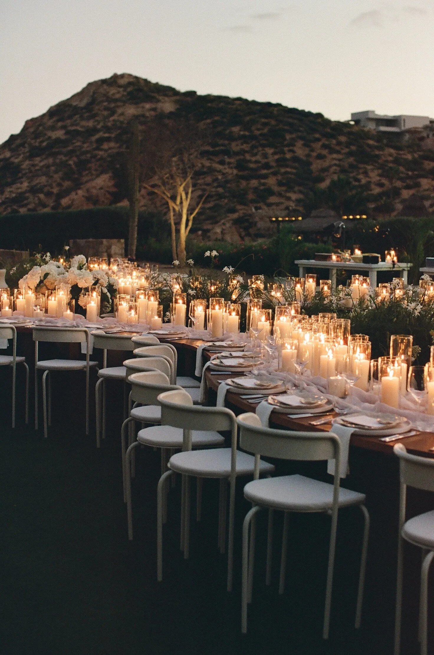 Long candlelit tables at dusk with the desert mountains behind, Montage Los Cabos