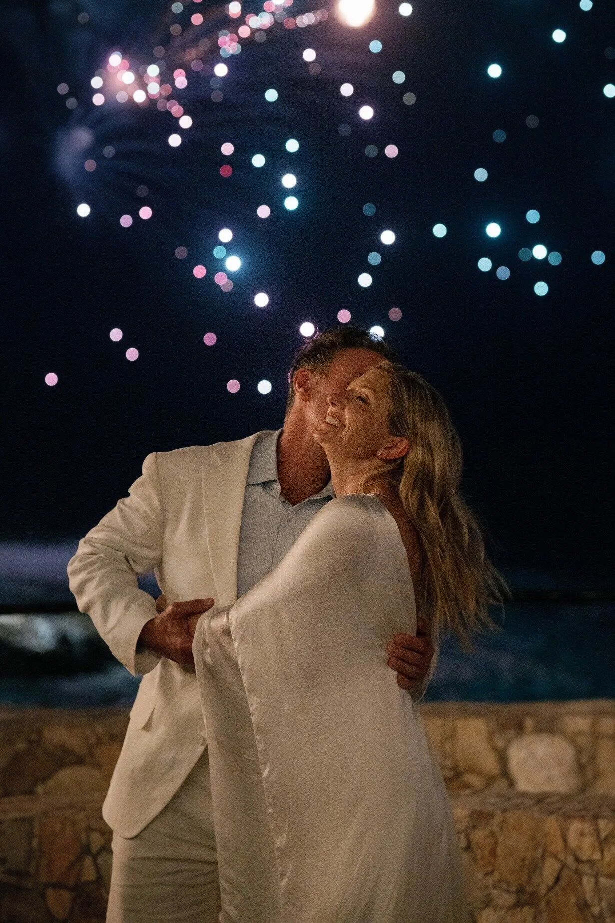 A bride under fireworks above the sea at the end of the night