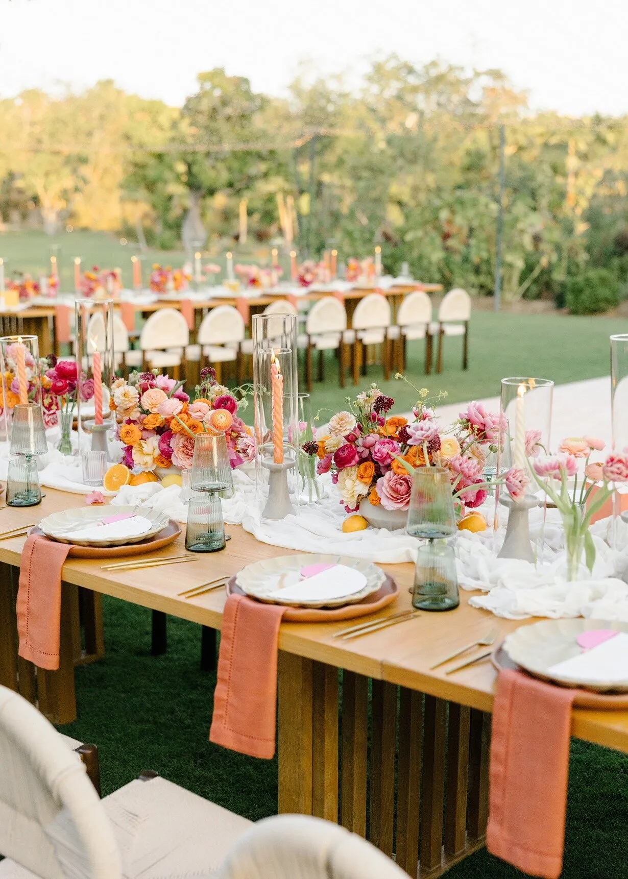 Long tables on the grass at Flora Farms, set with citrus-coloured flowers