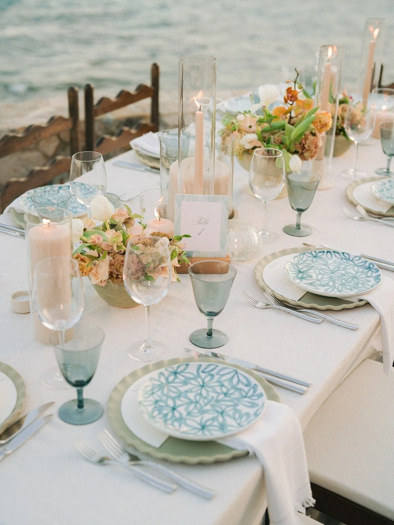 A table setting at the water's edge, hand-painted plates and candles