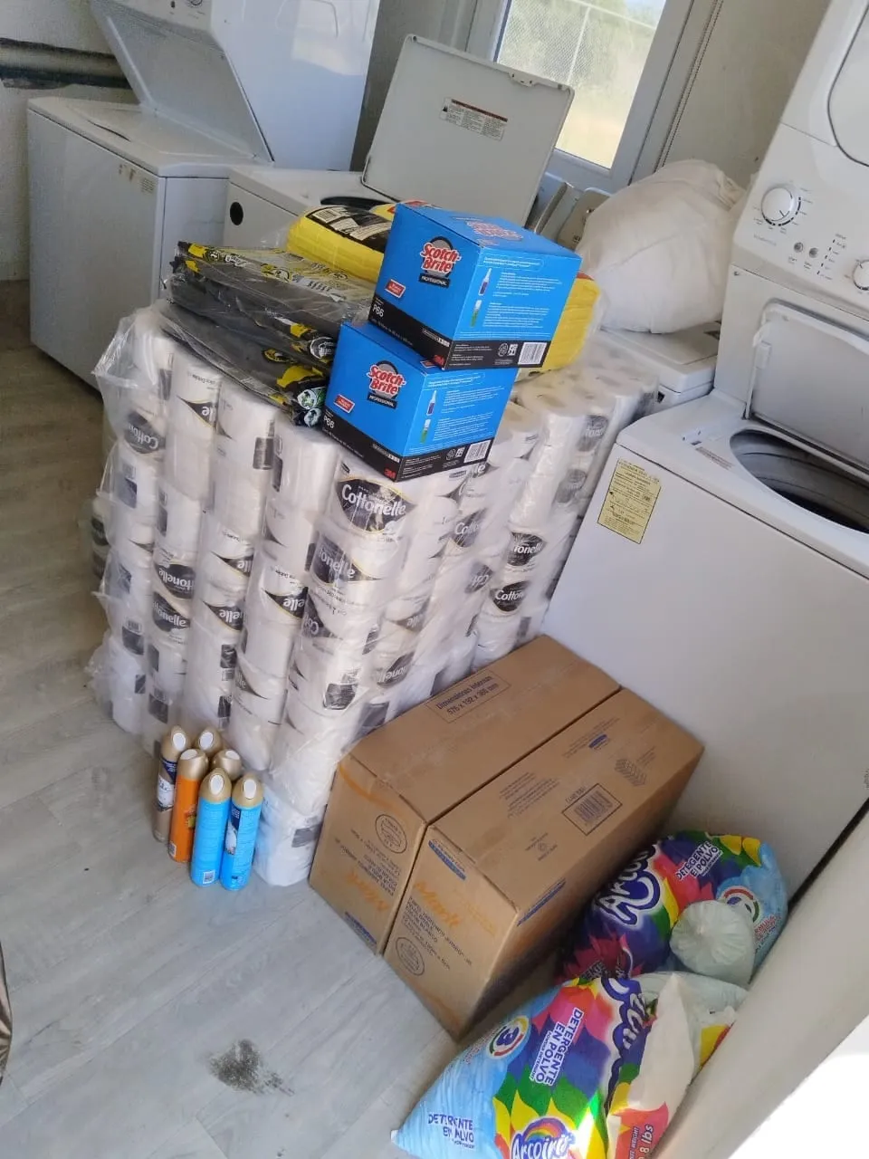 A delivery landed inside a laundry: paper, scouring pads and sacks of powder detergent beside the machines