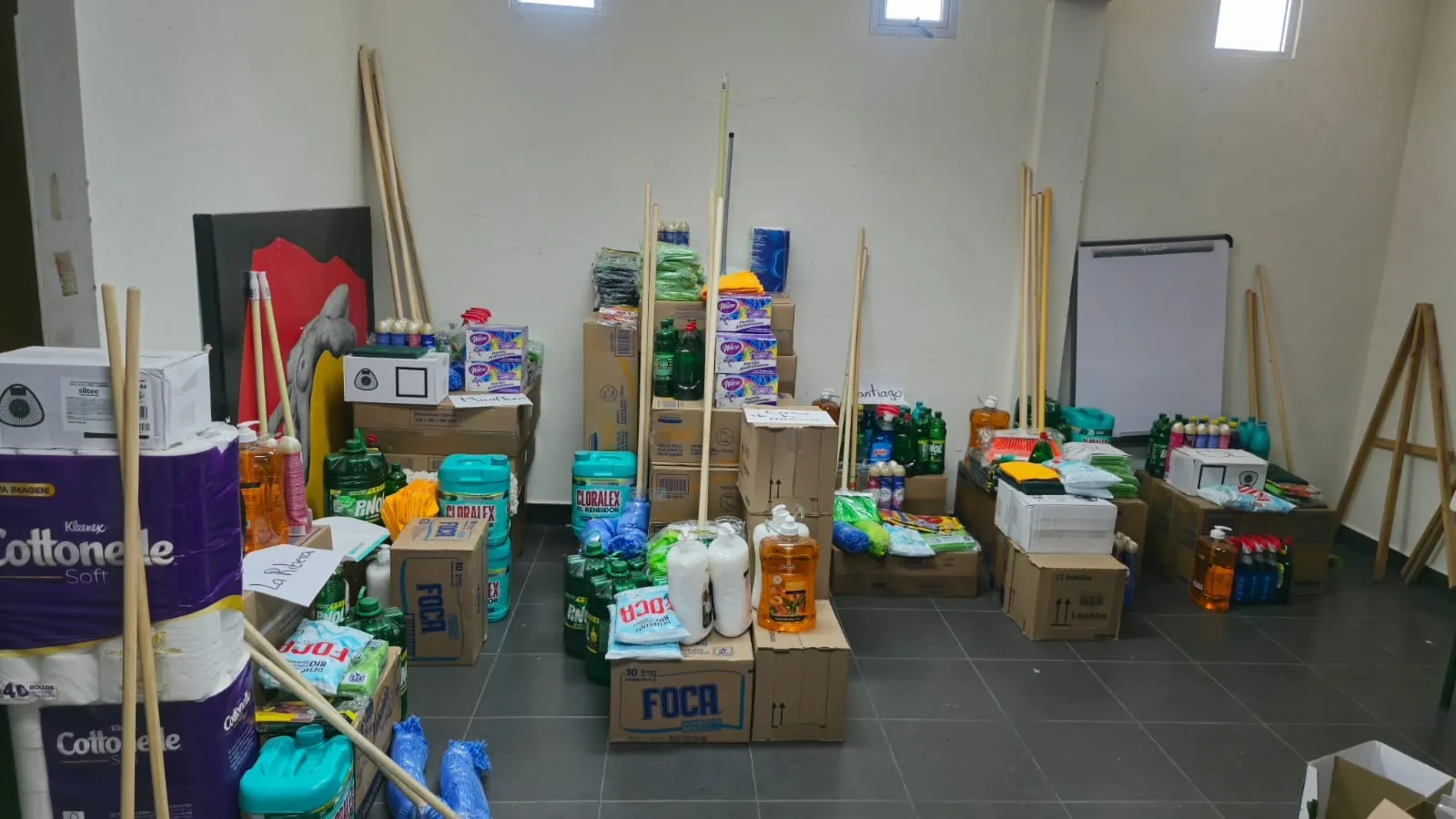 Orders staged on the warehouse floor under handwritten signs for each town on the route