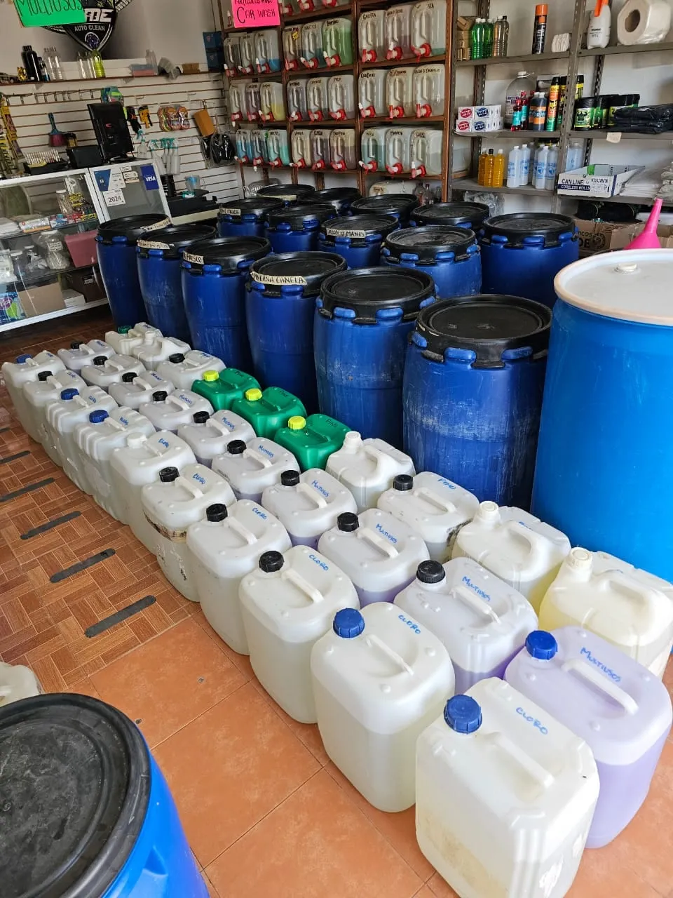 Rows of 20-litre jugs and blue drums of chlorine, degreaser and multi-surface cleaner on the shop floor