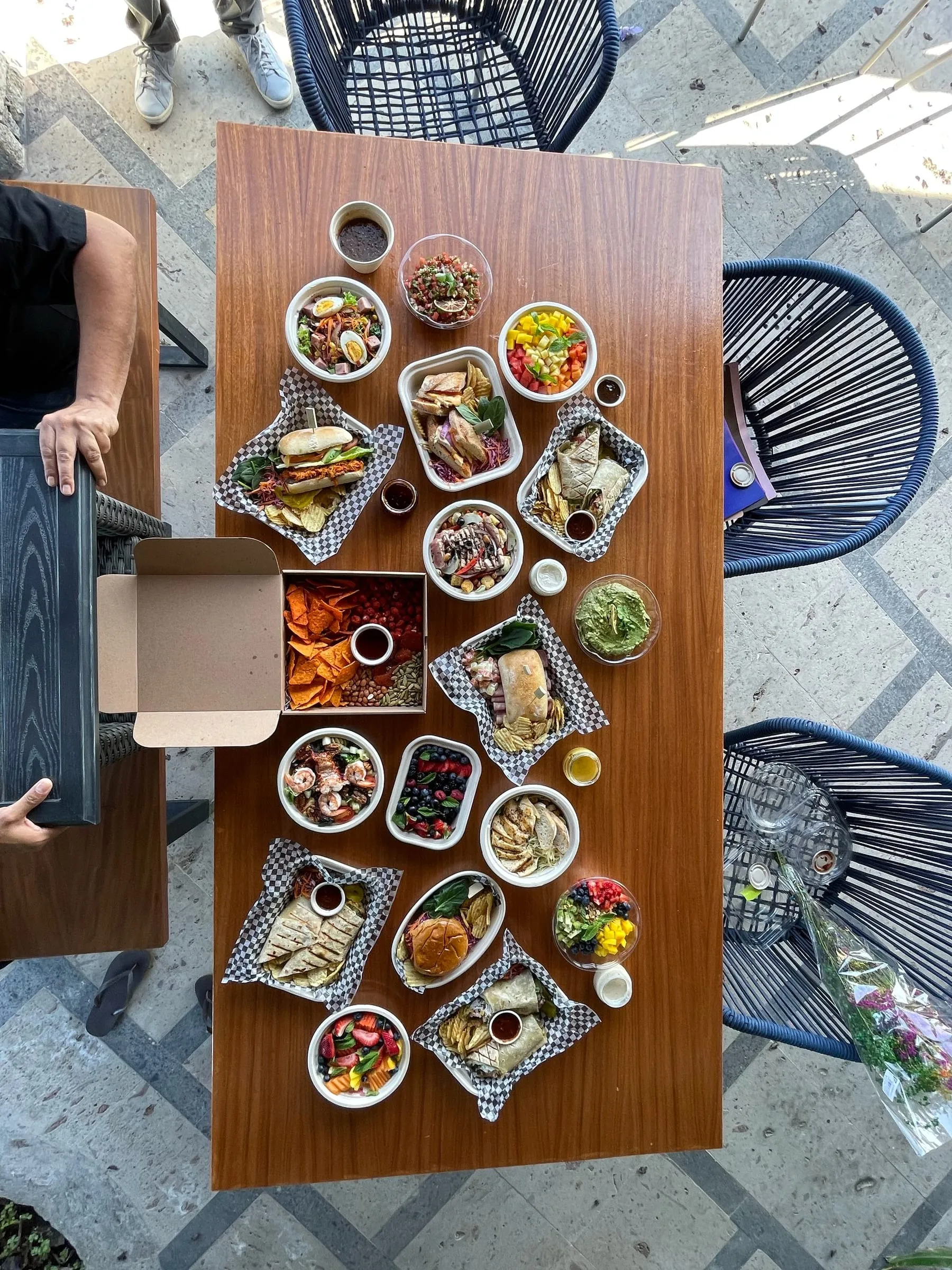 An outdoor table set with a family-style spread of small dishes, seen from above