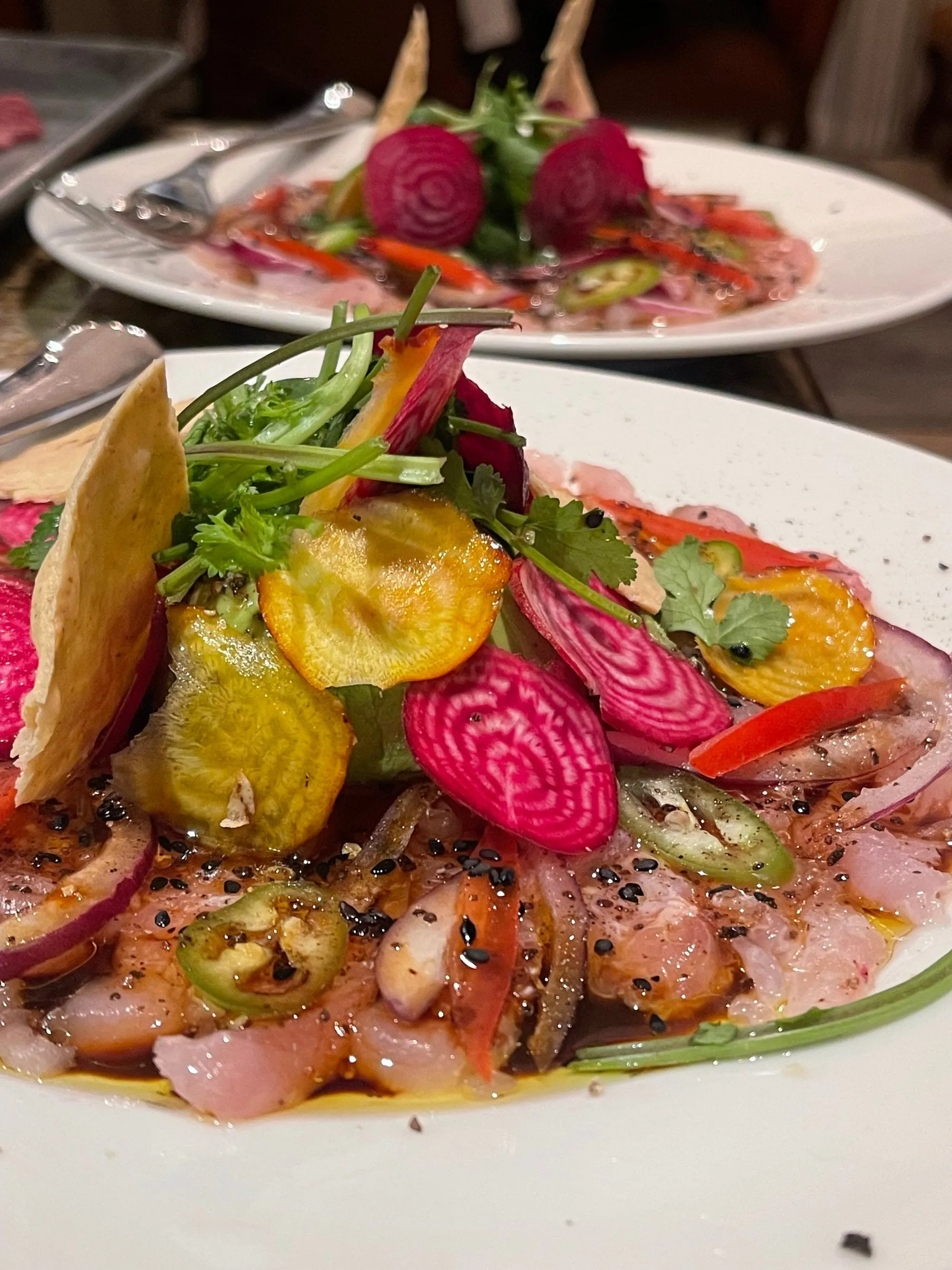 Thin-sliced raw fish under golden and candy-stripe beetroot, jalapeño, coriander and a tostada