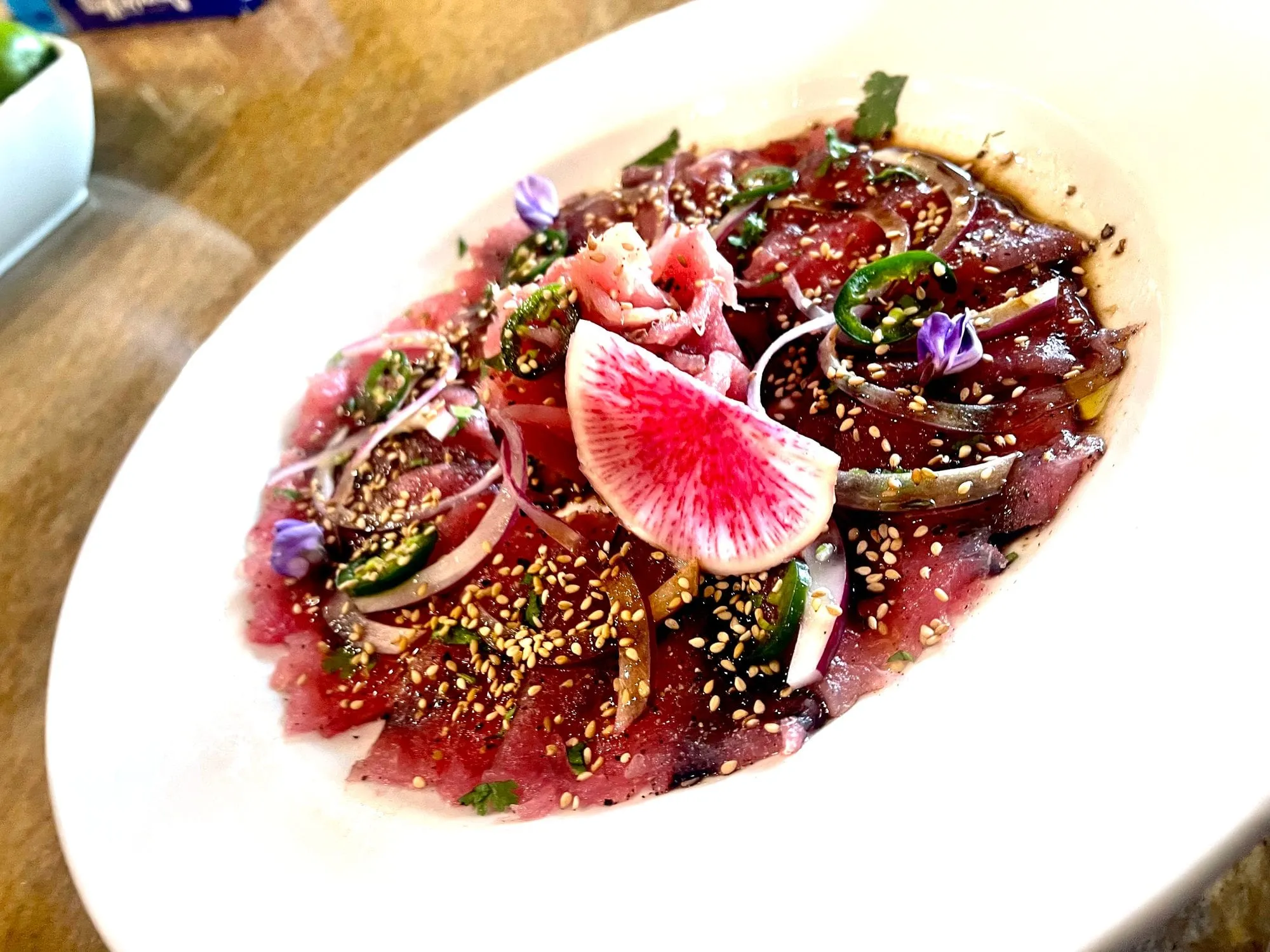 Tuna carpaccio with watermelon radish, sesame seeds and edible flowers