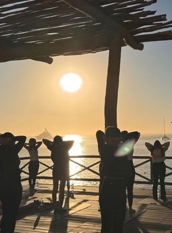 Hands raised against the sun setting over the water at the end of a session