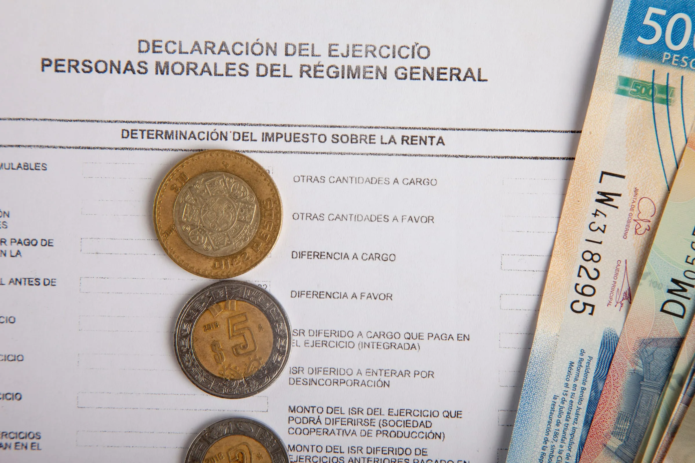 A Mexican declaración del ejercicio form for personas morales, with pesos laid across it