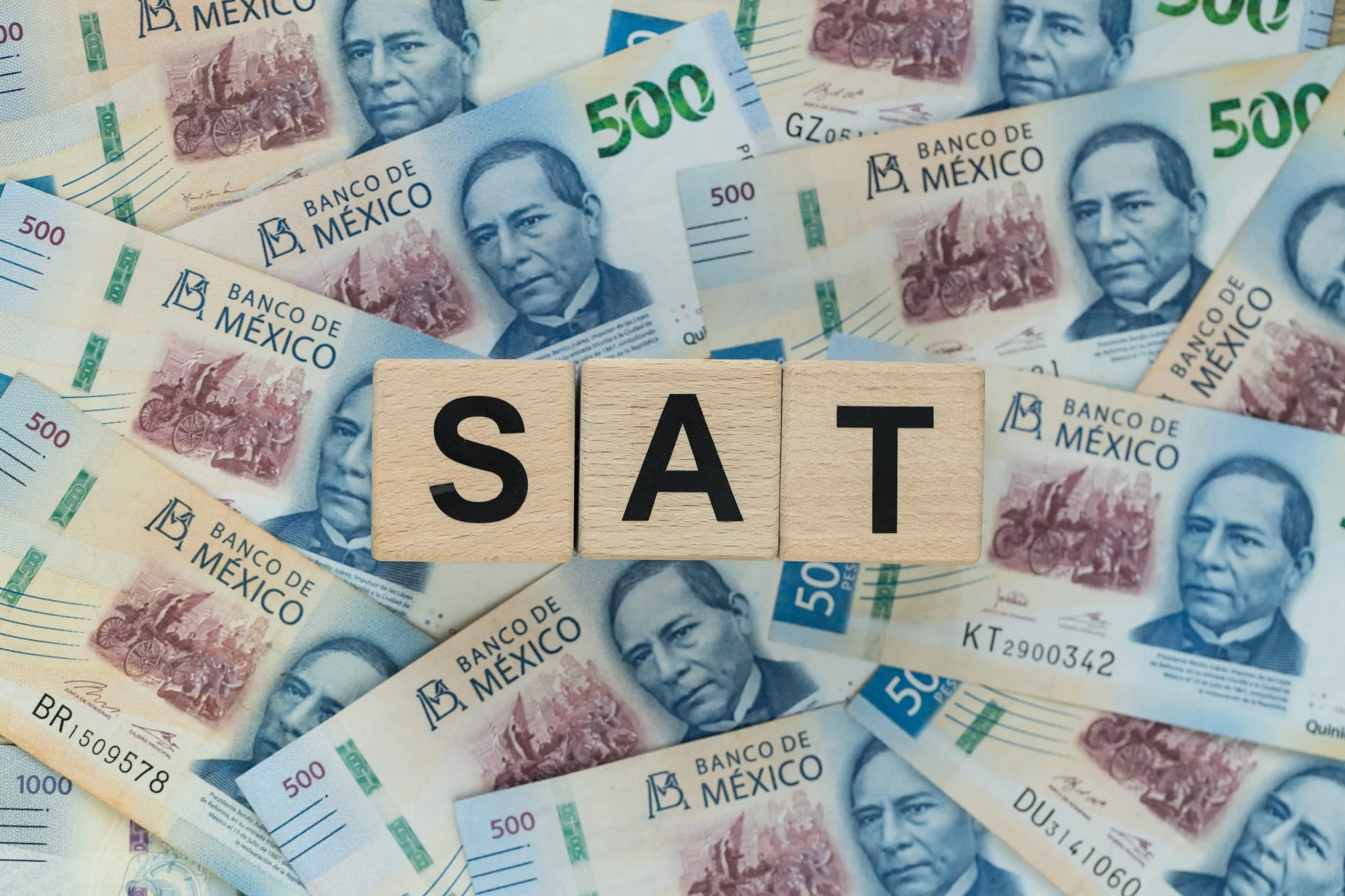 The letters SAT spelled in wooden tiles across five-hundred peso notes