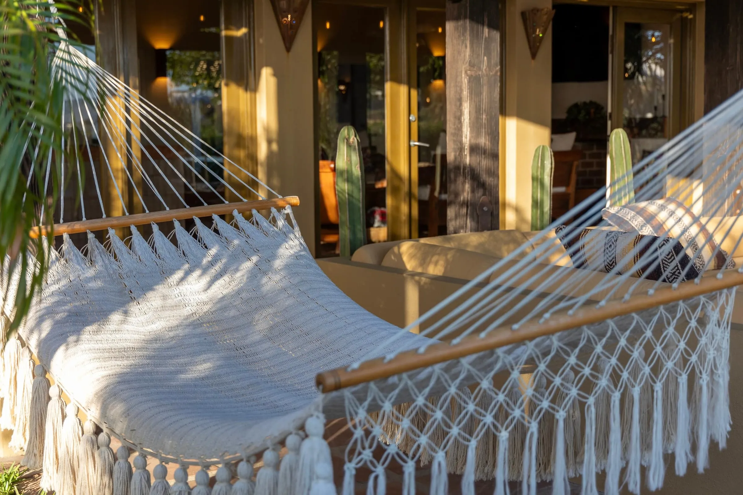 A hammock strung on the terrace outside the lit windows of the house